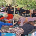 People doing yoga outside under a large tent at Redricks Lake