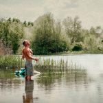 man standing in the lake embracing the sunshine