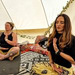 Two ladies in yoga pose in the ceremony space at the Conscious Heart traveling healing village for festivals.